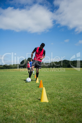 Soccer player dribbling through cones