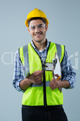 Male architect holding clipboard and blueprint against white background