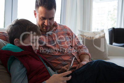 Father and son using digital tablet in living room