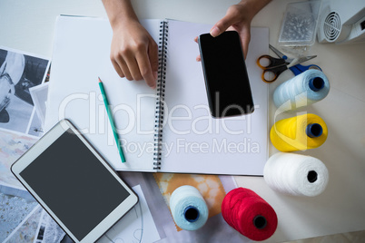 Fashion designer using mobile phone at desk