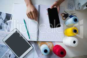 Fashion designer using mobile phone at desk