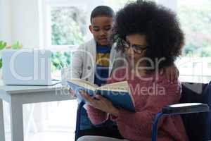 Son and his disabled mother reading a book