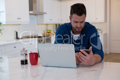 Handsome man using mobile phone in kitchen