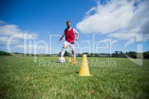 Soccer player dribbling through cones