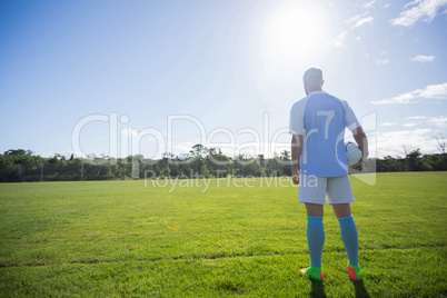 Football player holding soccer in the ground