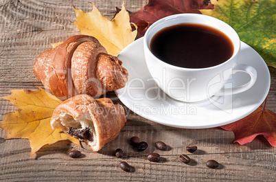 Coffee with a croissant on a wooden table