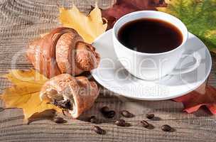 Coffee with a croissant on a wooden table