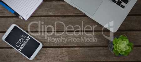 Composite image of laptop, pot plant, notepad, pen and mobile phone on wooden plank