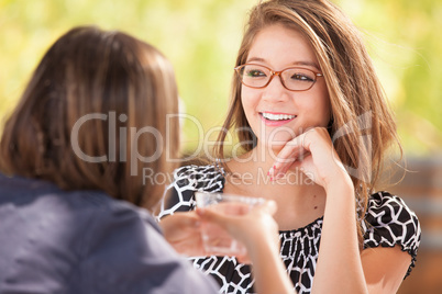 Two Mixed Race Girlfriends Talking Over Drinks Outdoors