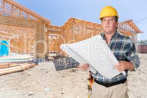 Male Contractor With House Plans Wearing Hard Hat In Front of Ne