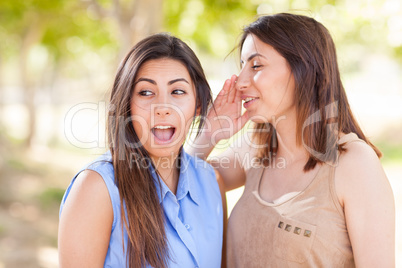 Two Beautiful Ethnic Twin Sisters Whispering Secrets Outdoors.