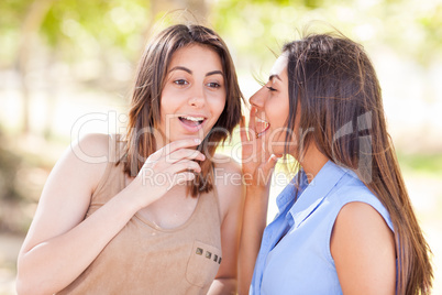 Two Beautiful Ethnic Twin Sisters Whispering Secrets Outdoors.
