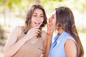 Two Beautiful Ethnic Twin Sisters Whispering Secrets Outdoors.