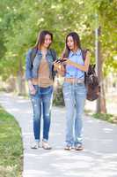 Two Beautiful Young Ethnic Twin Sisters With Backpacks Using A S