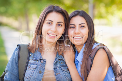 Two Beautiful Young Ethnic Twin Sisters With Backpacks Walking O