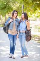 Two Beautiful Young Ethnic Twin Sisters With Backpacks Walking O