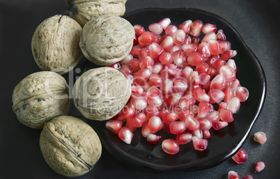 Pomegranate fruits on the plate and walnuts.