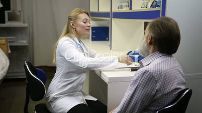 Female doctor checking senoir man's temperature