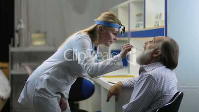 Doctor examining man's throat with tongue depressor