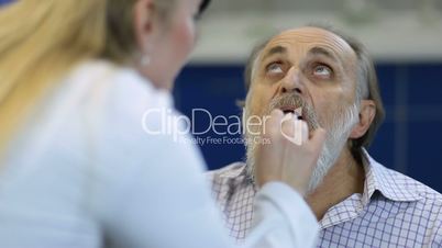 Senior man at the physician checking his throat