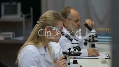 Scientists working on microscopes in laboratory