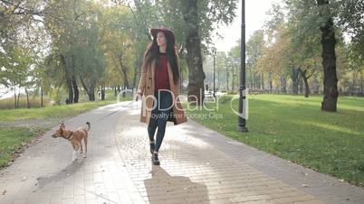 Elegant woman walking with dog in autumn park