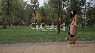 Woman taking a stroll with dog in autumn park