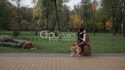 Smiling young woman stroking dog in autumn park