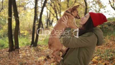 Beautiful hipster girl holding dog in autumn park
