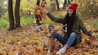 Hipster woman and dog playing with fallen leaves