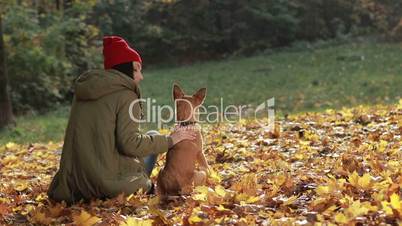 Charming woman and her dog posing in autumn park