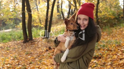 Smiling playful girl with dog on autumn day