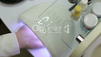 Client drying gel polished nails in UV light