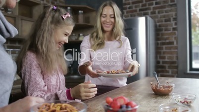 Cheerful mother offering daughter homemade cookies