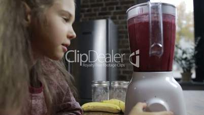 Adorable girl preparing fresh smoothie in blender