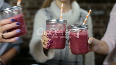 Females toasting berry smothies in mason jars