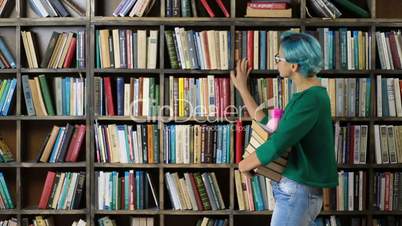 Female student choosing book on shelf in library