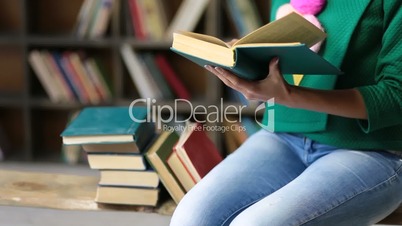 College student carrying pile of books in library