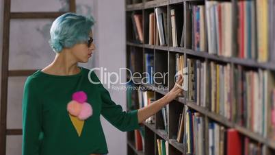 Hipster girl searching for book in a bookstore