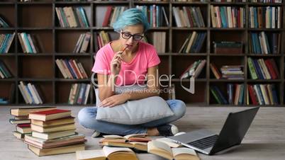 Female student researching with books and laptop