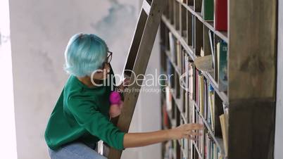 Girl standing on ladder searching book in library