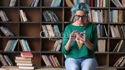 Carefree female student using phone in library