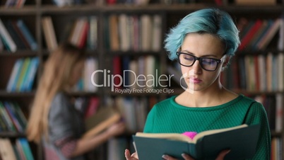 Hipster girl absorbed in reading book in library