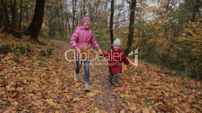 Joyful children running through autumn woodland