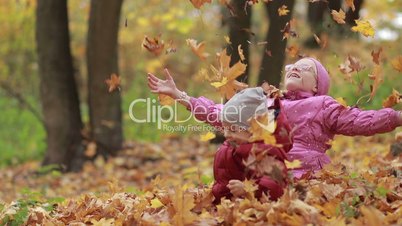 Cheerful children playing in leaves pile in autumn
