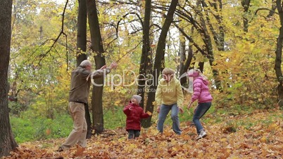 Grandparents and children with leaves in autumn