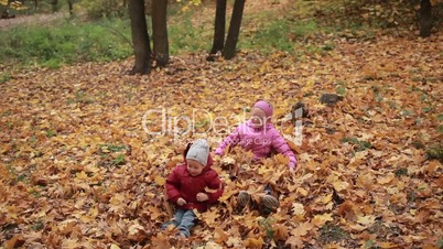 Carefree kids playing in a pile of fall leaves