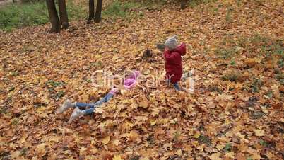 Cheerful siblings jumping in pile of autumn leaves