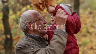 Grandpa with toddler boy resting in autumn park