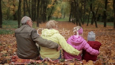 Multi-generation family embracing in autumn park